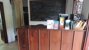 A wooden reception desk with a blackboard, a computer, and various items on top.