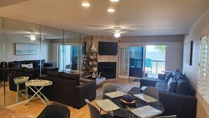 A living room with a fireplace, a dining area with a glass table, and a balcony with a view.