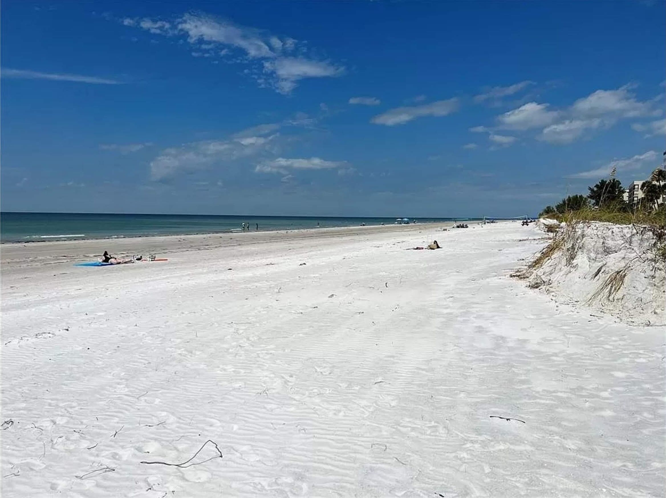 A wide sandy beach with a clear sky and calm sea.