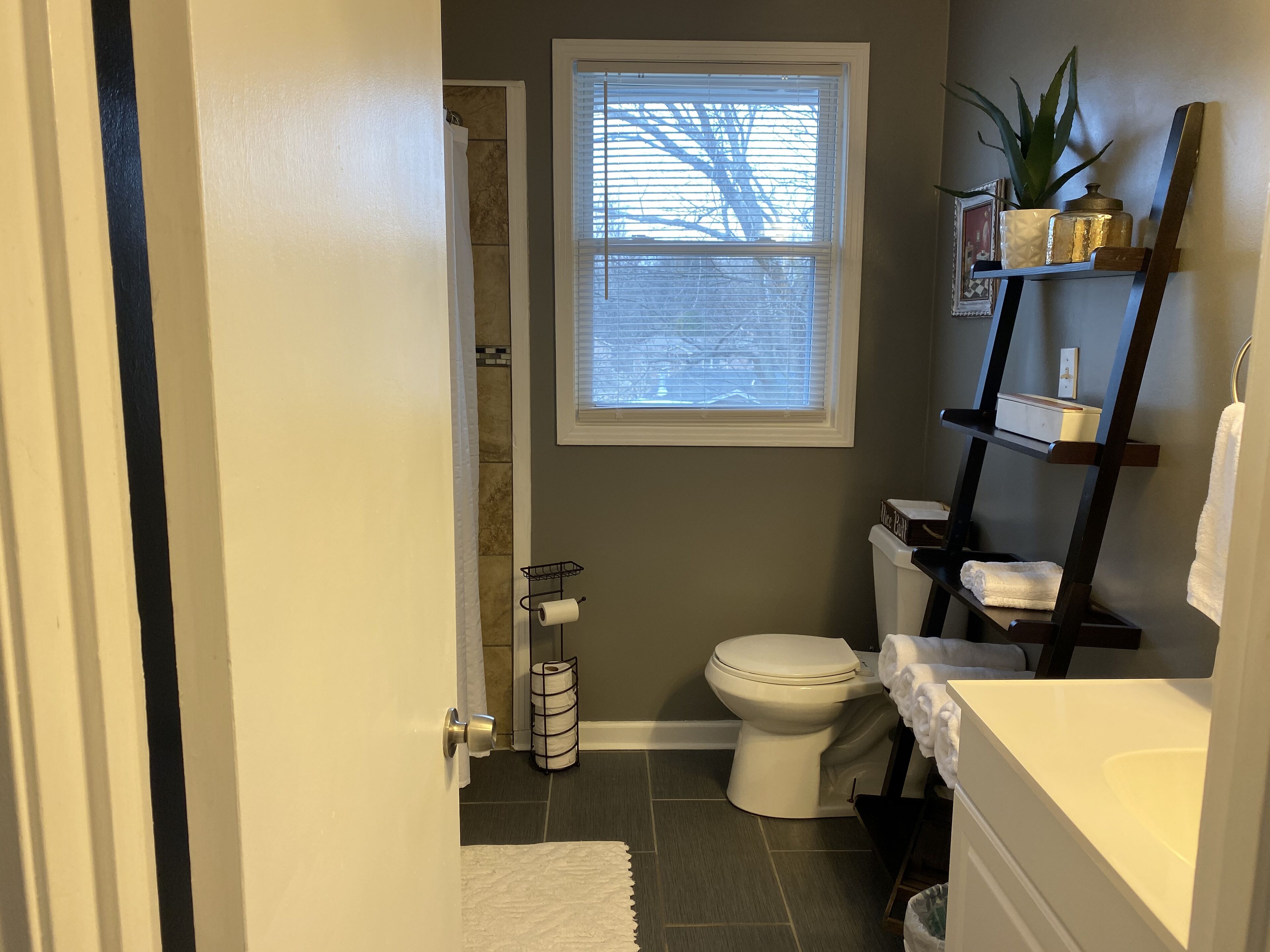 Een badkamer met toilet, wastafel, douche en een raam.