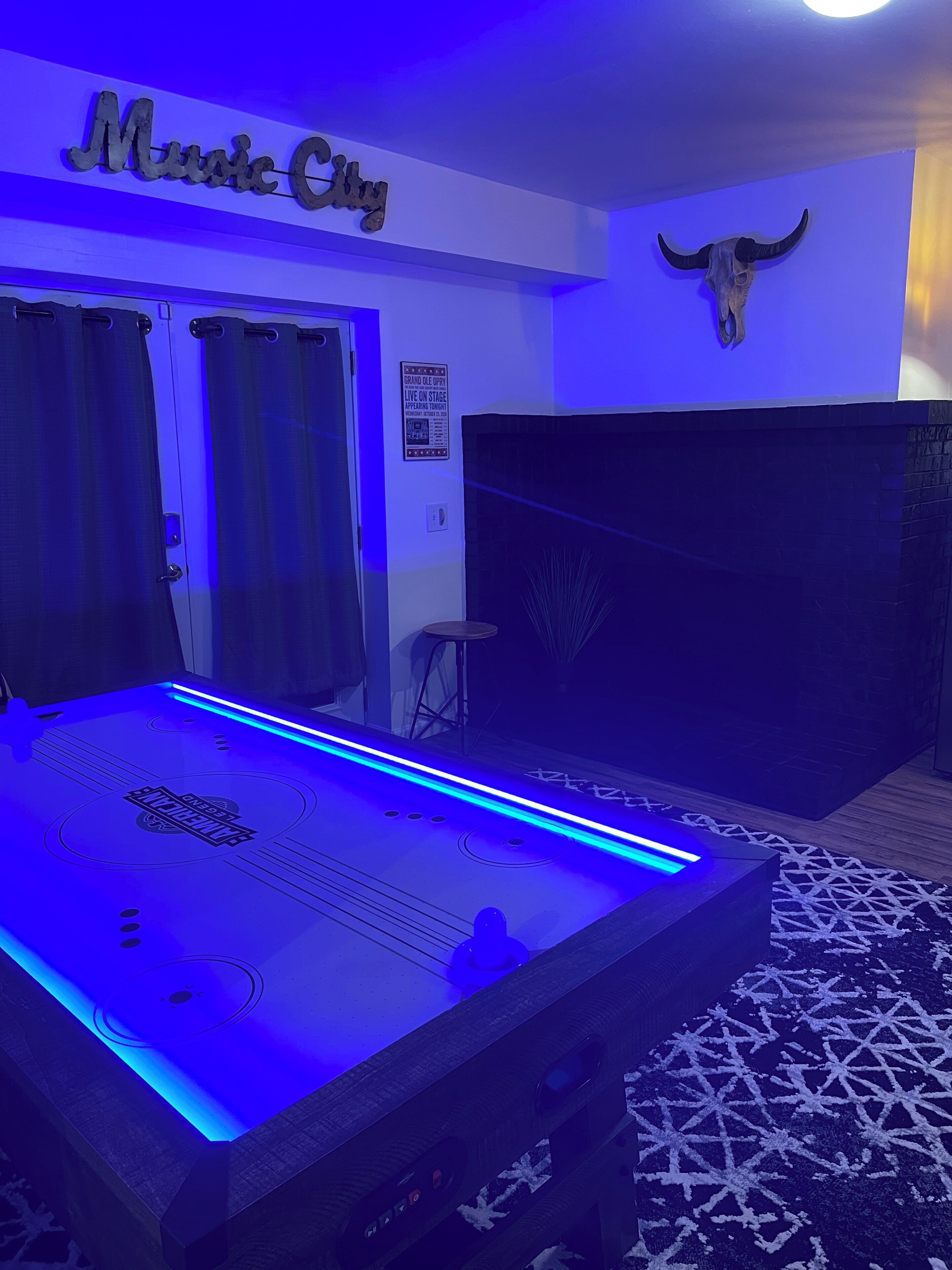 A room with a foosball table, a wall-mounted bull skull, and a sign for live music events.