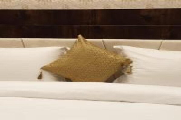 A white sofa with a textured gold pillow. - GANGA DARSHAN HOTEL AND RESORT (Varanasi)