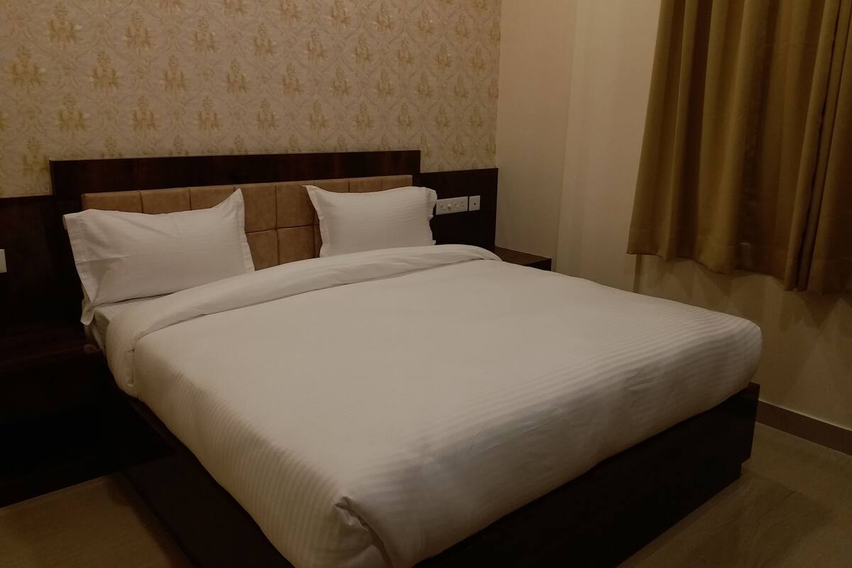 A neatly made bed with white linens in a hotel room.