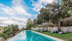 Una piscina con sillones de descanso y una pared de piedra.