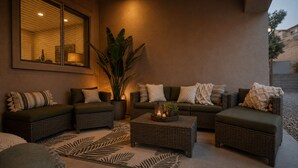 Un rincón exterior acogedor con mobiliario de mimbre, una planta grande en maceta y un adorno decorativo.