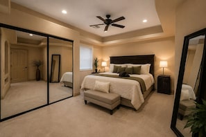 Une chambre à coucher avec un lit, des tables de chevet, un ventilateur de plafond et un grand miroir.