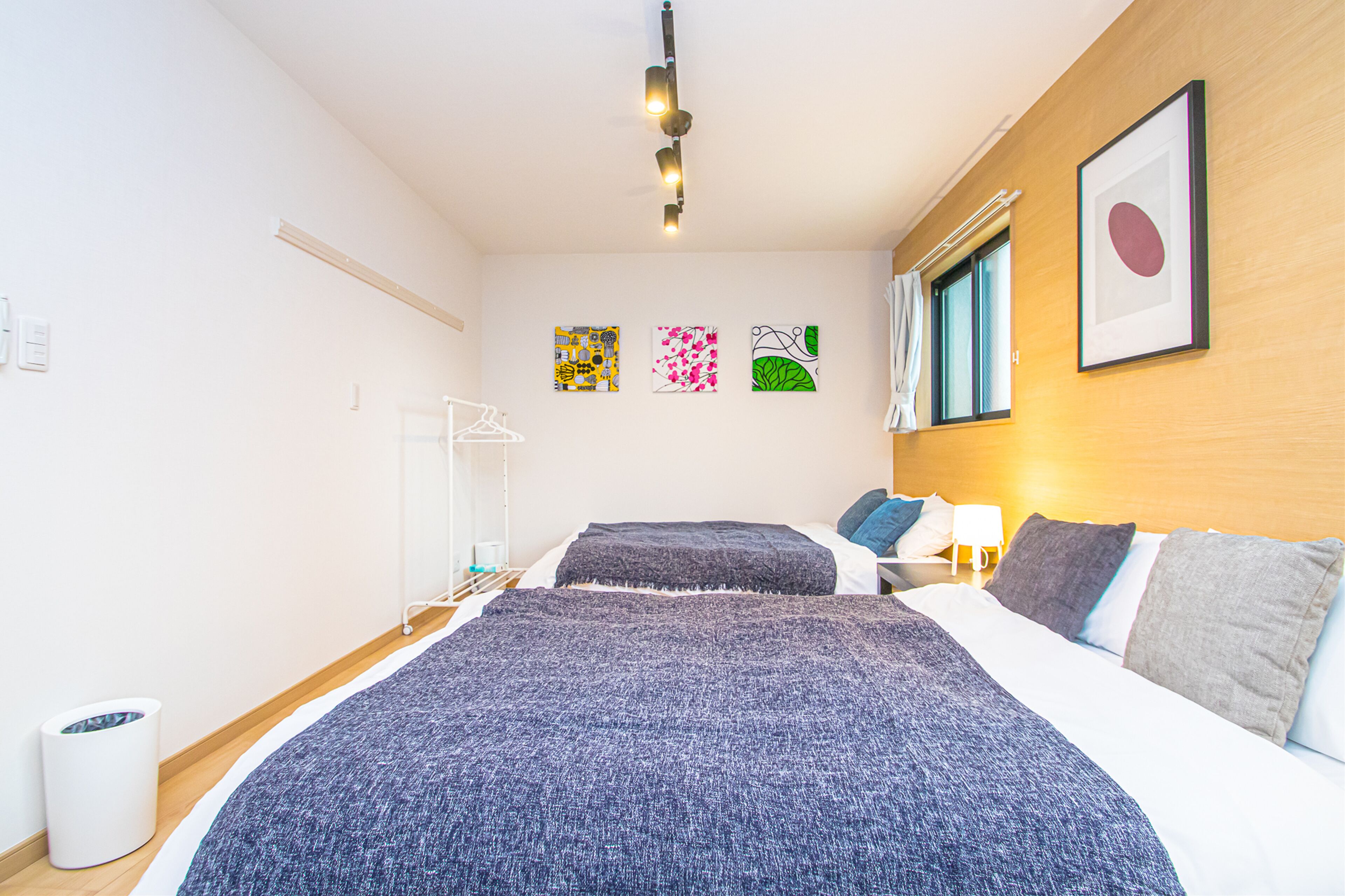 A hotel room with a large bed, a bedside table, a wall-mounted light, and three framed artworks.