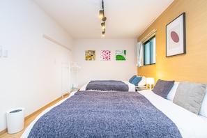 A hotel room with a large bed, a bedside table, a wall-mounted light, and three framed artworks. - LA-CHIC Stay Hakata Ⅰ (Fukuoka)