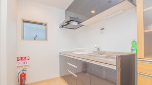 A modern kitchen with stainless steel appliances, a window, and a fire extinguisher. - LA-CHIC Stay Hakata Ⅰ (Fukuoka)
