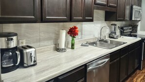 A modern kitchen with dark wooden cabinets, stainless steel appliances, and a marble countertop. - Charming 3 bdr. Condo in Central Raleigh (Raleigh)