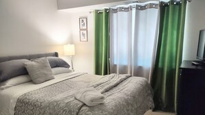 A neatly made bed with a patterned bedspread, a bedside lamp, and a television on a stand. - Charming 3 bdr. Condo in Central Raleigh (Raleigh)