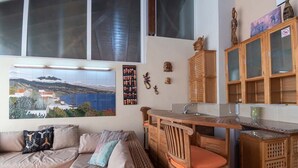 Uma sala de estar aconchegante com um sofá, uma mesa de jantar de madeira e uma cozinha com armários.