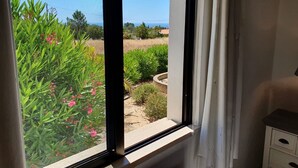 A room with a large window overlooking a garden with various plants and flowers. - Villa with pool and sea view.  Quiet location, beach and restaurants nearby. (Carvoeiro)