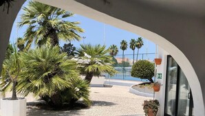 A covered outdoor area with a tiled floor, palm trees, and a building entrance with glass doors. - Villa with pool and sea view.  Quiet location, beach and restaurants nearby. (Carvoeiro)