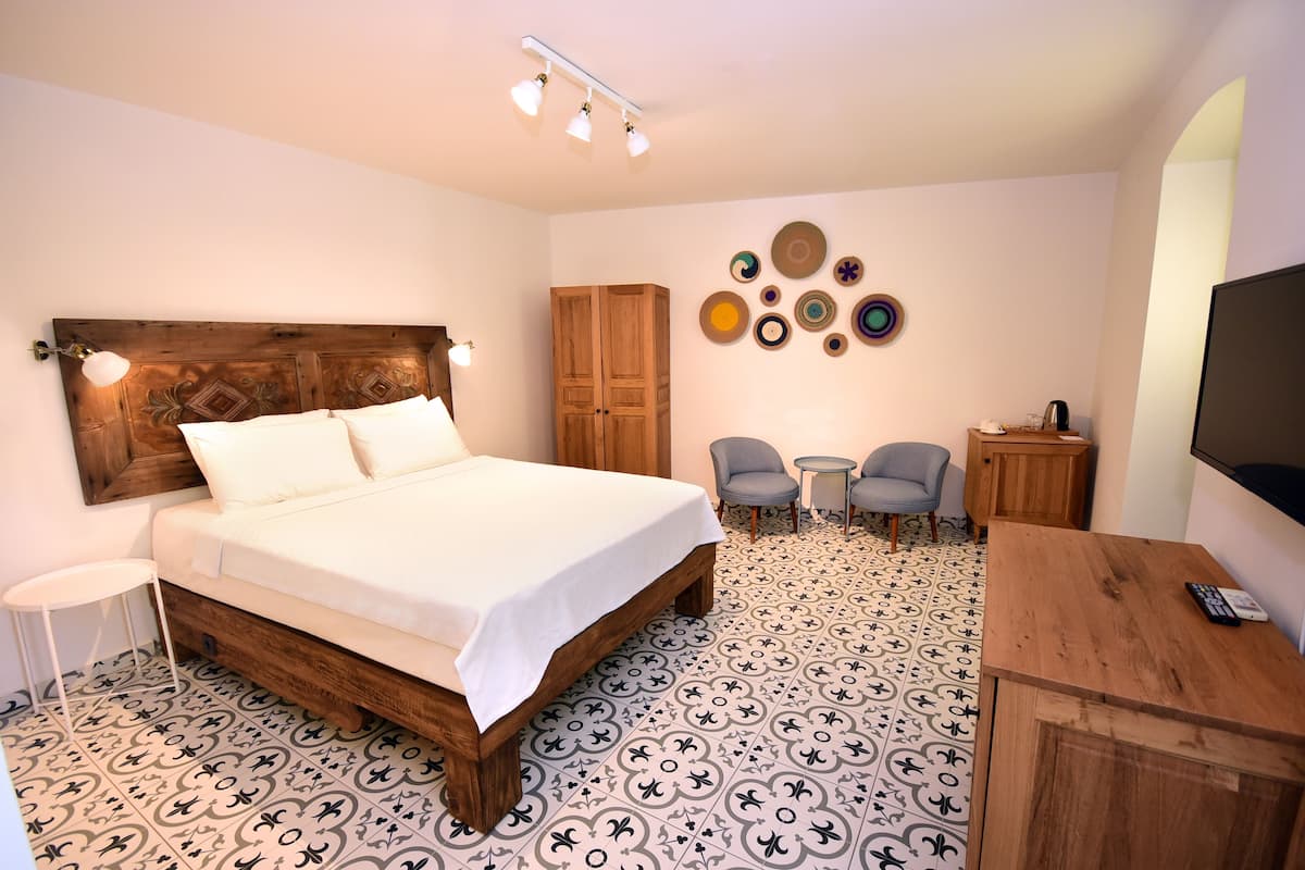A bedroom with a wooden bed, a small desk, a chair, and a TV.
