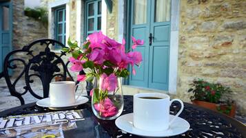 A table with a magazine, a vase with pink flowers, and two cups of coffee.