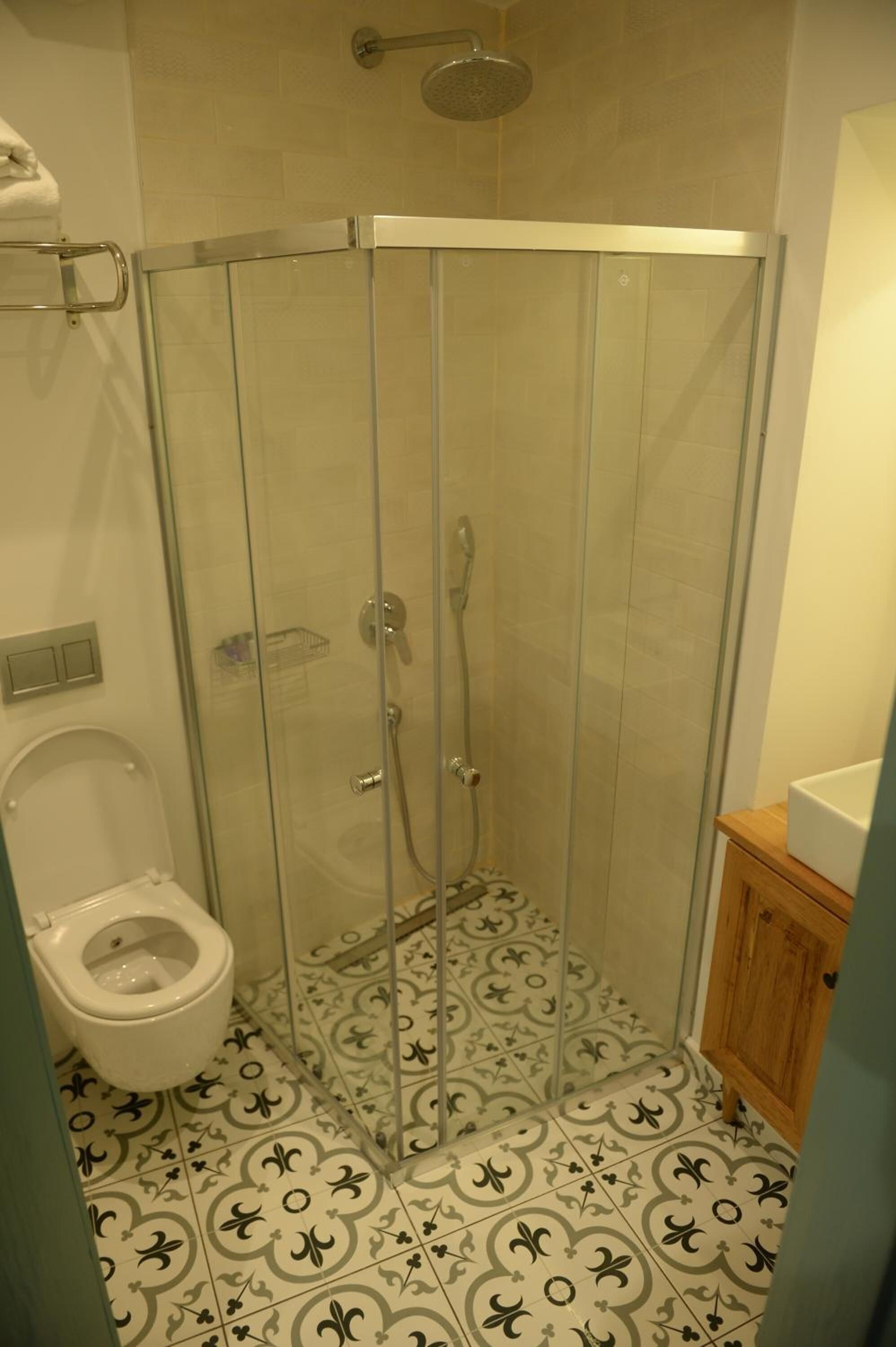 Een kleine, afgesloten douchecabine met een glazen deur, een toilet en een houten kast.