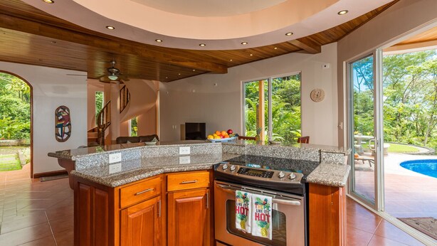 A kitchen with a central island, wooden cabinets, and a built-in oven. - Stunning 180 degree Ocean, Mountain and Jungle Views! (Ojochal)