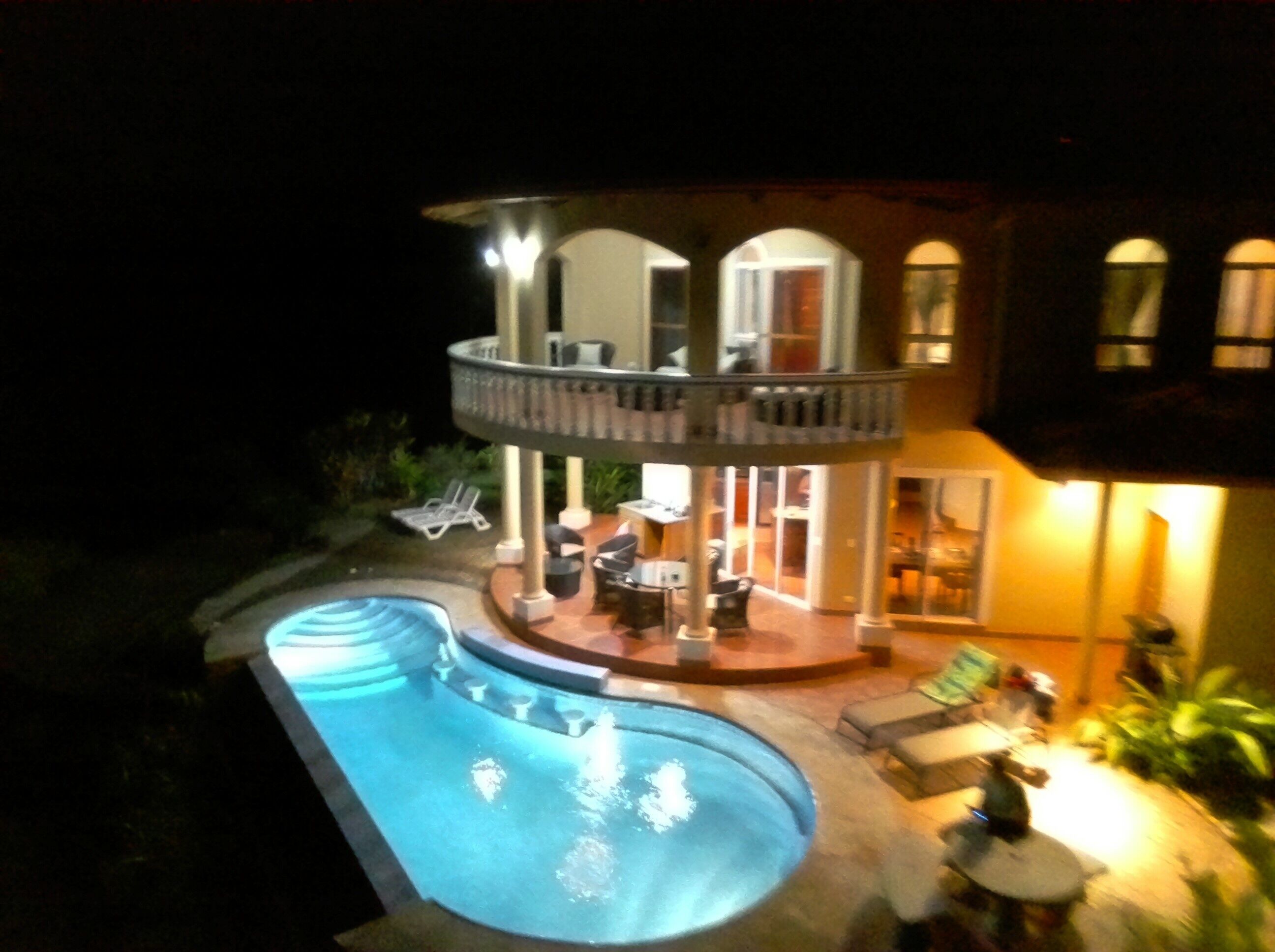 A two-story house with a swimming pool, outdoor seating, and a balcony.