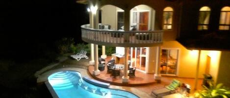 A two-story house with a swimming pool, outdoor seating, and a balcony.