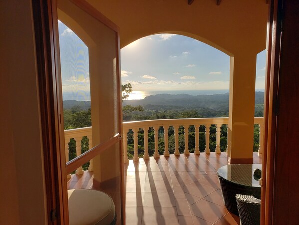Un balcon offrant une vue sur un paysage montagneux et un coucher de soleil.