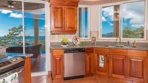 A kitchen with wooden cabinets, a dishwasher, and a granite countertop. - Stunning 180 degree Ocean, Mountain and Jungle Views! (Ojochal)