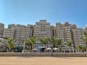Ein großes Hotel mit mehreren Etagen, Balkonen und einem sandigen Vordergrund.