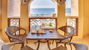 Comedor con una mesa y cuatro sillas de mimbre, con vistas a la playa.