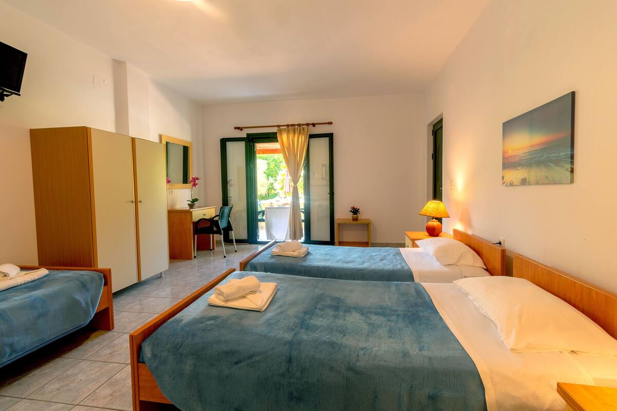 A hotel room with two beds, a desk, a chair, and a window with curtains.