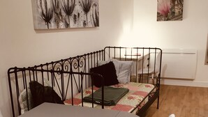 Un coin repas comprenant un canapé à structure métallique, une table et des chaises blanches.