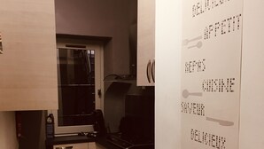 Une cuisine de taille réduite, avec un carrelage au sol, un four à micro-ondes, une cuisinière et des placards.