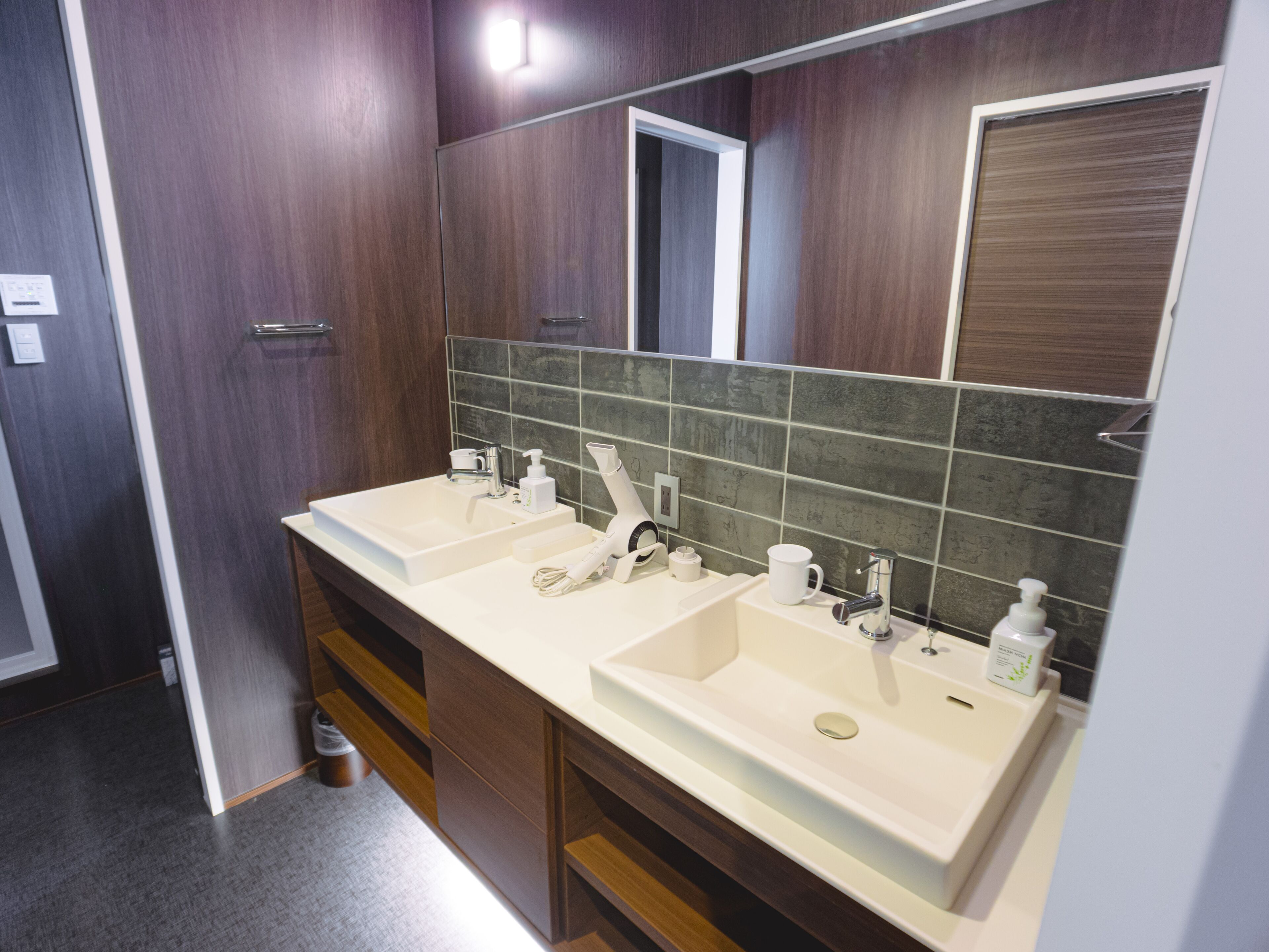 A modern bathroom with two sinks, a mirror, and a towel rack.