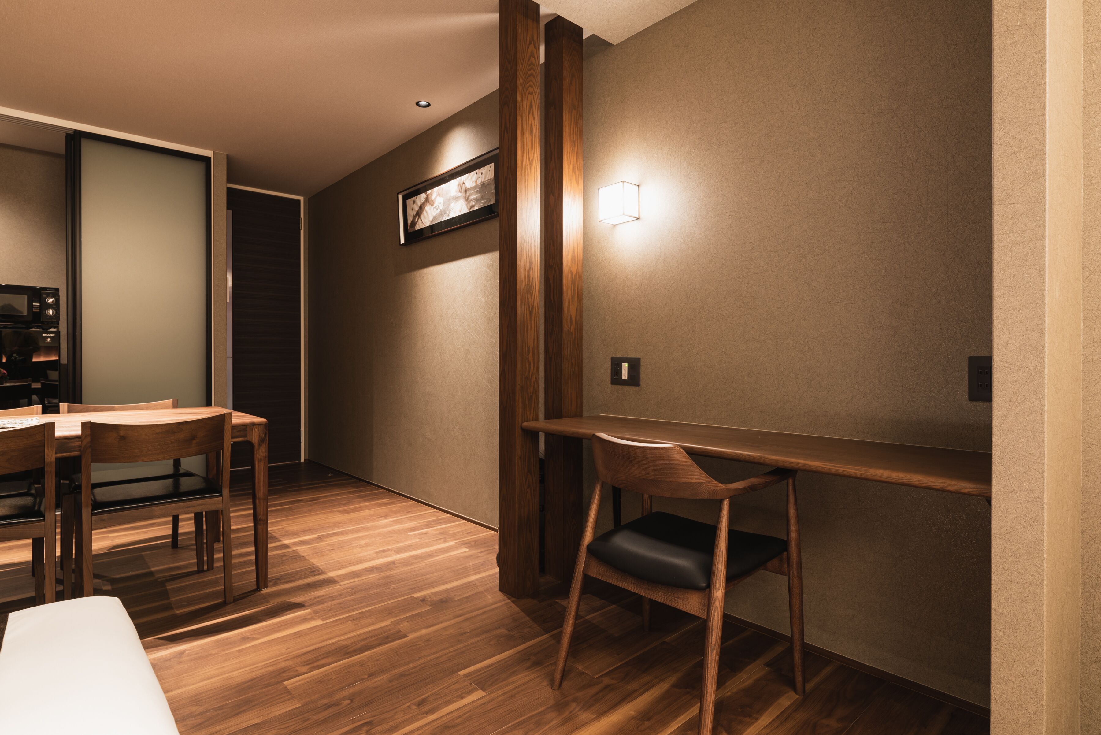Une chambre moderne avec un bureau en bois, une chaise et une table à manger avec des chaises.