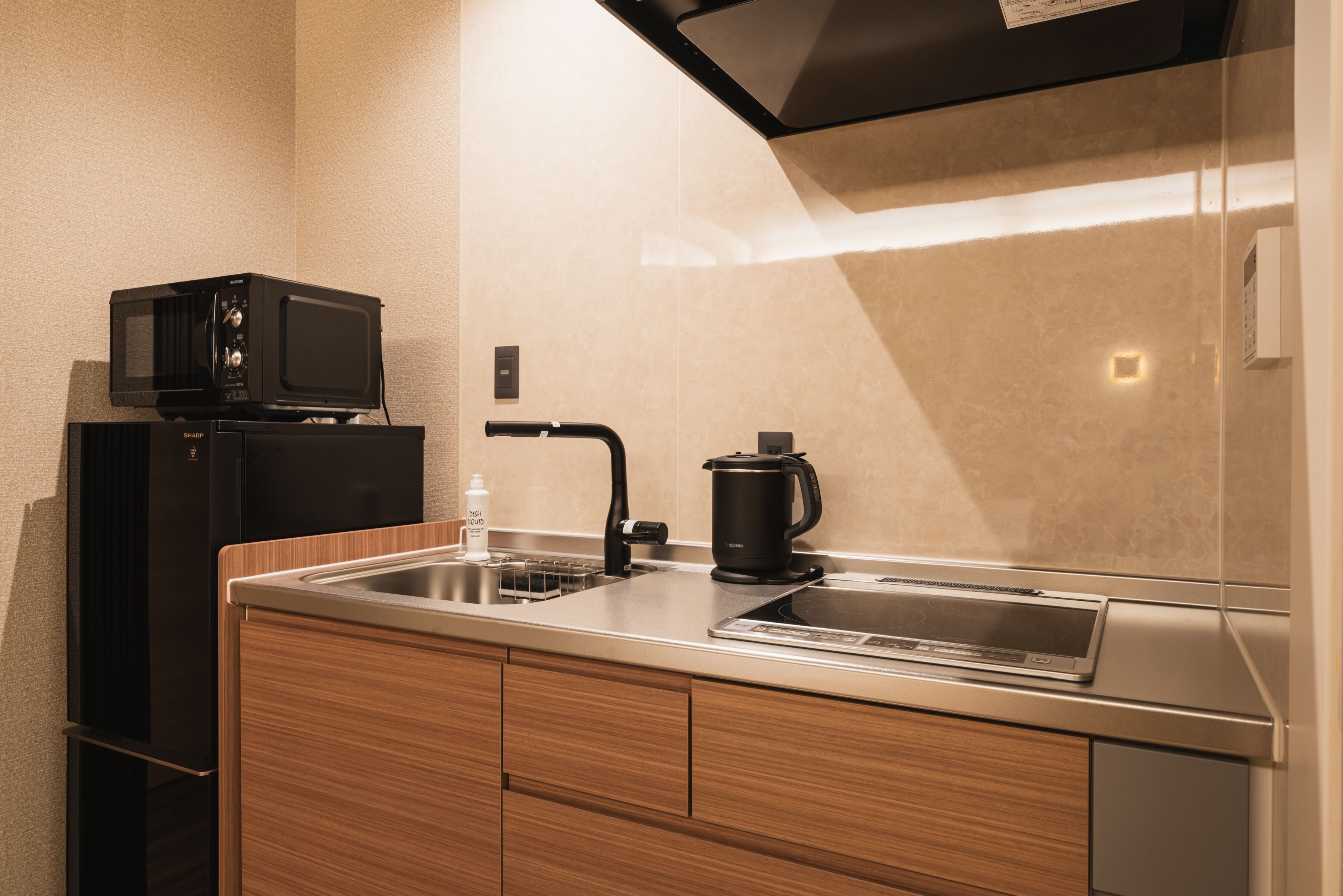 A compact kitchen with a microwave, coffee maker, and a sink.