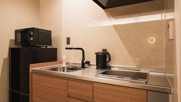 Una cocina compacta con microondas, cafetera y lavamanos.