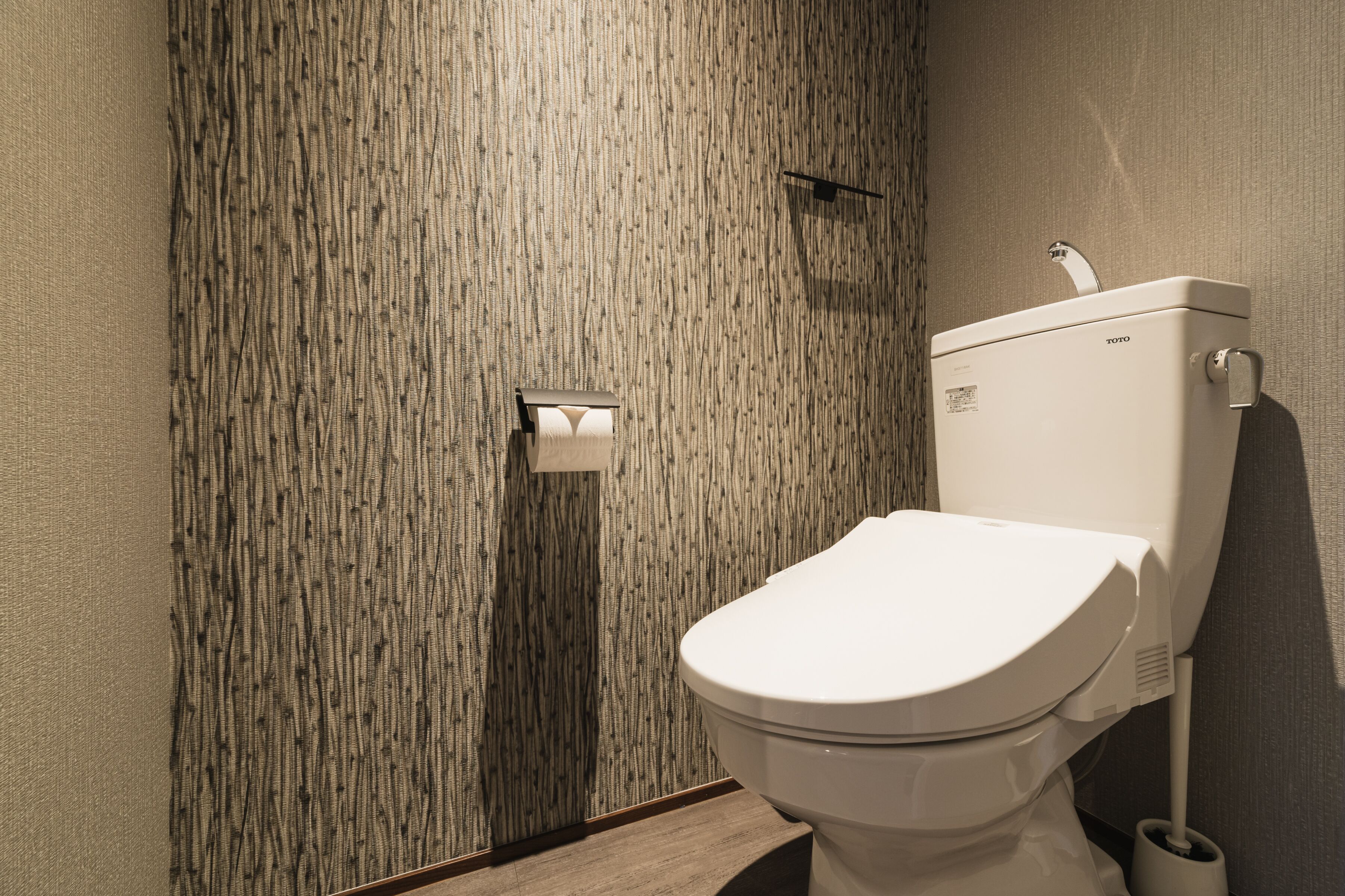 Un baño moderno con una pared con textura, un inodoro blanco y un bidé instalado en la pared.