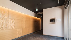 Ein Flur mit strukturierter Wand, einem Empfangsbereich und einer Tür mit einem Schild.
