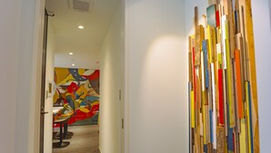 A hallway with a wooden floor and a colorful abstract painting on the wall. - Bond Base (Fukuoka)