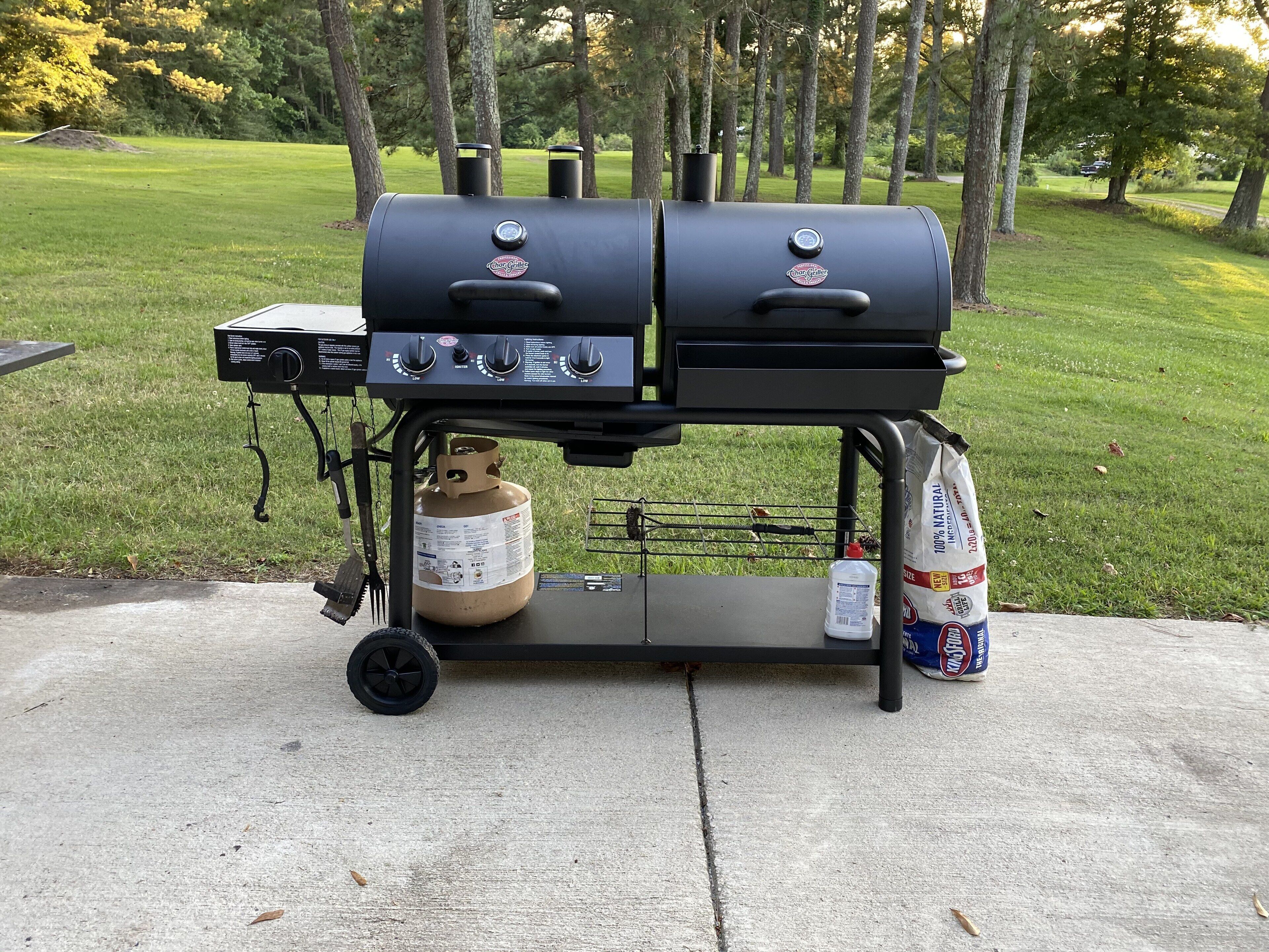 A portable barbecue grill with two burners, a side burner, and a gas tank.