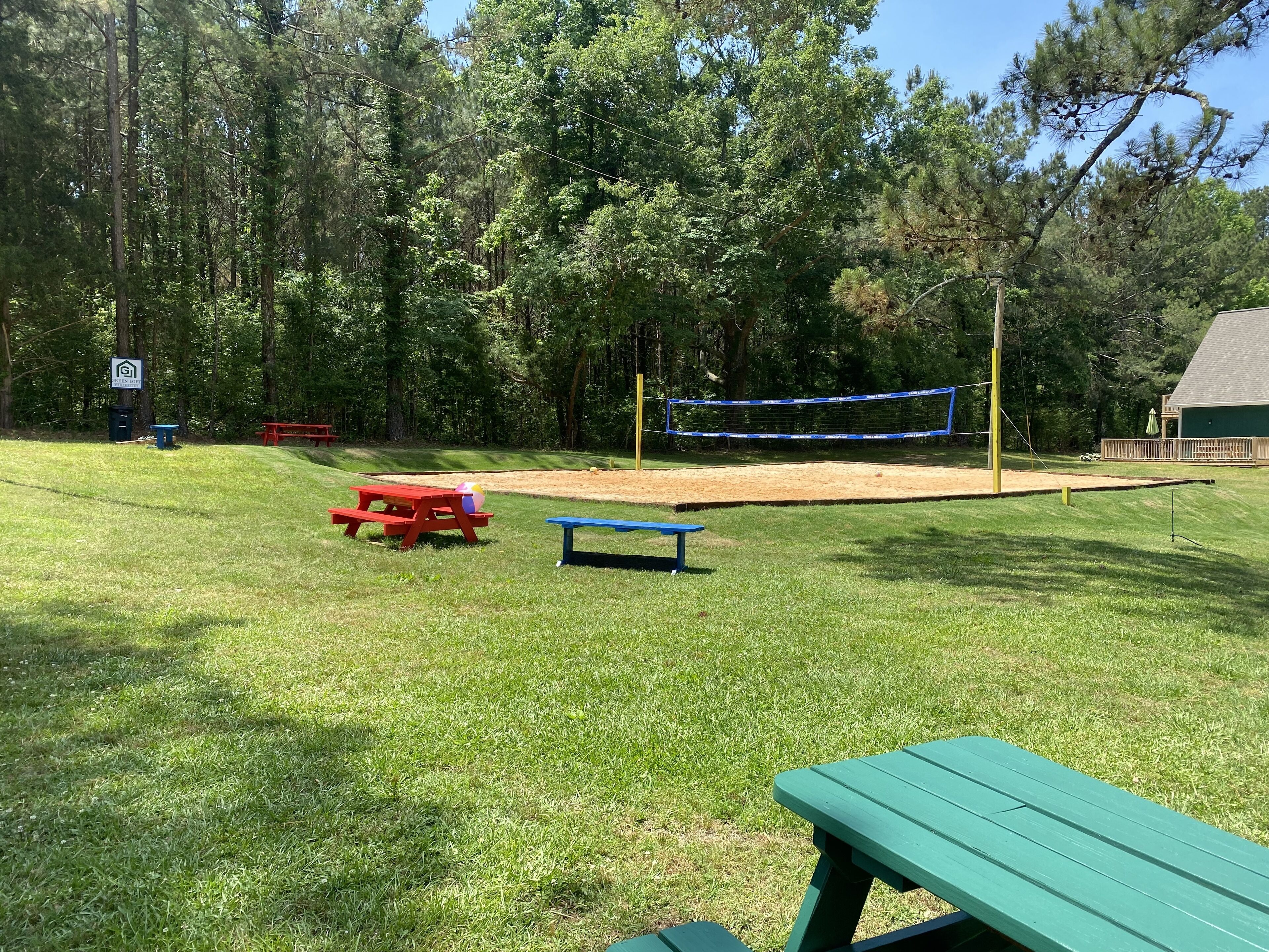 Uma área gramada com mesas de piquenique e uma rede de voleibol.