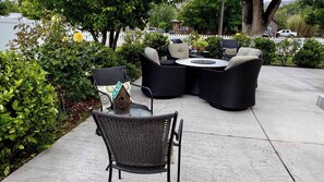 An outdoor patio with wicker furniture, a round table, and a decorative birdhouse.
