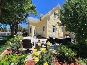 A yellow house with a patio area featuring outdoor furniture and a garden with yellow flowers.
