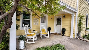 A yellow house with a porch, two rocking chairs with sun-shaped cushions, a potted plant, and a mailbox. - Stunning Historic Home in Kanab, Utah. Close proximity to Zion and Bryce Canyon. Incredible stargazing opportunities! (Kanab)