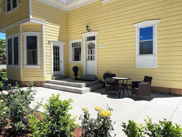 A yellow building with a front porch, a door, and a window.