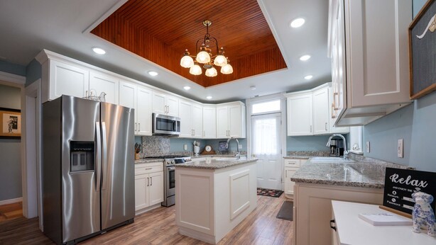 A modern kitchen with white cabinetry, stainless steel appliances, a wooden ceiling, and a granite countertop. - Stunning Historic Home in Kanab, Utah. Close proximity to Zion and Bryce Canyon. Incredible stargazing opportunities! (Kanab)