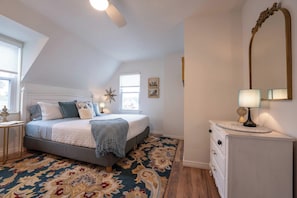 A bedroom with a bed, a nightstand, a mirror, and a window.