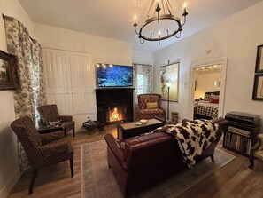 A living room with a fireplace, a television, and a chandelier.