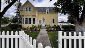A two-story house with a front porch, a picket fence, and a well-maintained lawn.