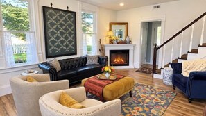 A living room with a fireplace, a sofa, a coffee table, and a staircase.
