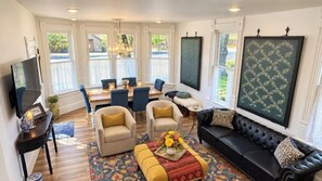 A living room with a sofa, armchairs, and a coffee table. There is a dining area with a table and chairs.